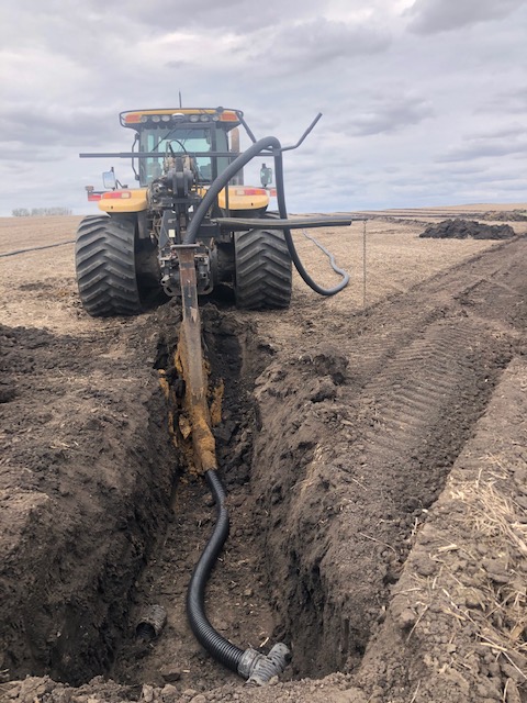 A tractor dropping tile into a field.